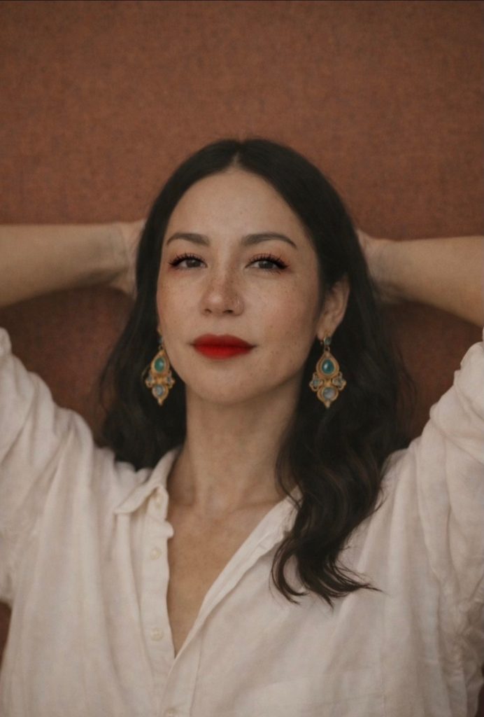 Portrait of a woman with red lips and gold earrings for Sunday Journal on healing and the good that comes after survival