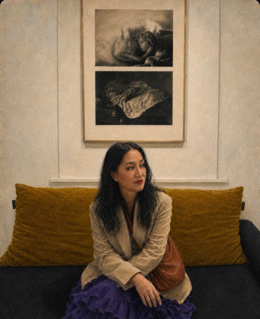 Painterly illustration of Bettina seated on a dark sofa beneath photographs by Michael Ackerman, wearing a light jacket, purple skirt and red lipstick, looking to the side in quiet reflection.